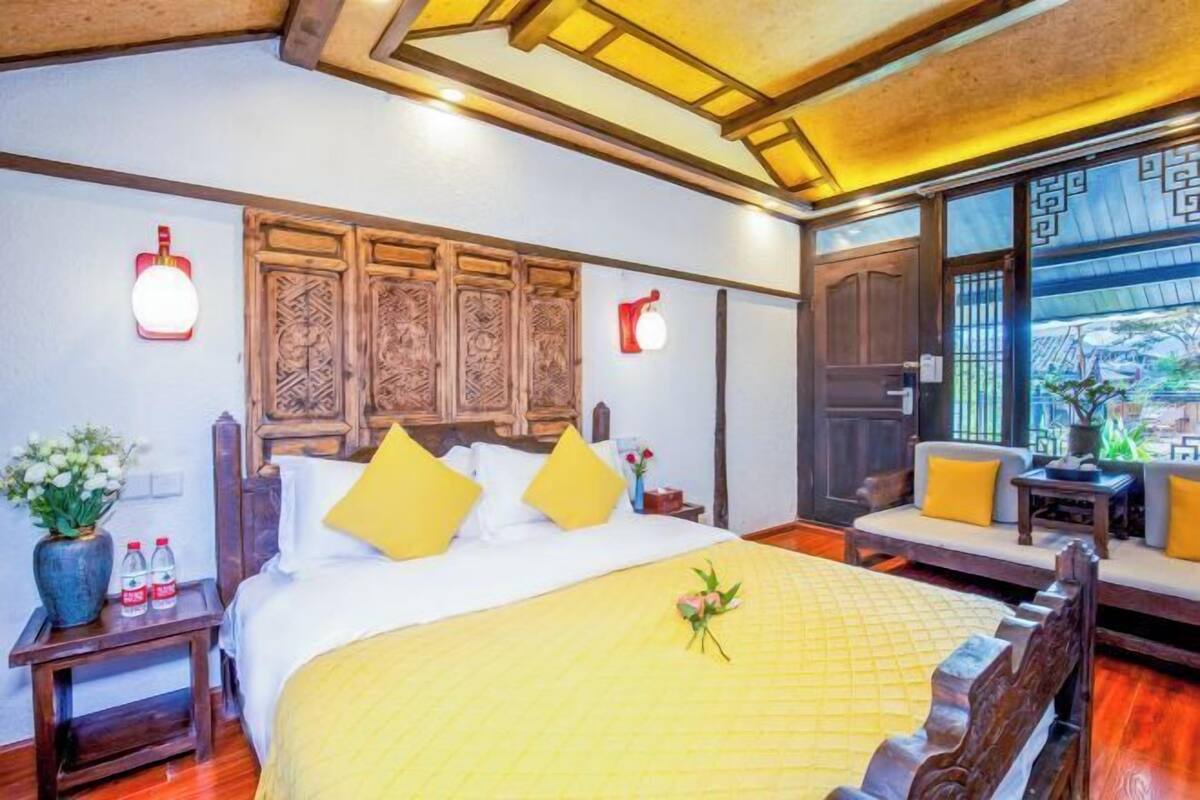 A traditional room with a bed, wooden headboard, and a sofa with cushions.