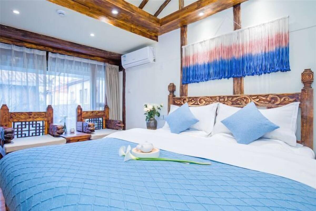 A bedroom with a large bed, wooden headboard, and a wall-mounted air conditioner.