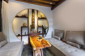 A cozy room with a wooden table, a sofa, and a circular shelf with decorative items. - ‌The Secret Garden of Cats & Wolf's Den Barista Courtyard Cafe & Inn (Wuyi Street) (Lijiang)