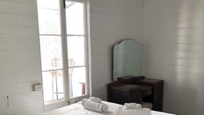 A hotel room with a bed, a dresser, a mirror, and a window with a view.