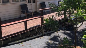 A building with a green roof, a porch with a wooden bench, and a window with a chair outside.