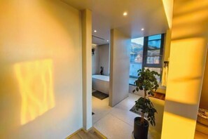 Un interior moderno con una bañera, una planta en maceta y vistas al exterior.