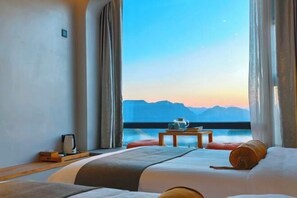 A hotel room with a bed, a small table with a cup and saucer, and a view of mountains through large windows. - Yunduan Hostel (Suichang)