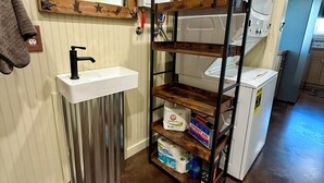 A bathroom with a sink, mirror, and shelves with toiletries.