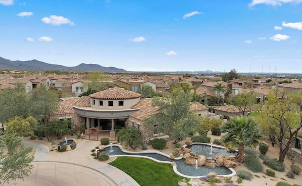 A residential area with houses, a swimming pool, and a mountainous backdrop.