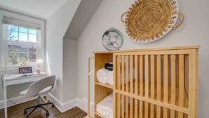 Une pièce comprenant un bureau, une chaise, un berceau et un objet circulaire fixé au mur.