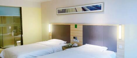 A hotel room with two beds, a glass partition, a painting, and a small desk with a telephone.