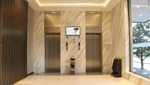 A modern elevator lobby with marble walls, a digital display, and a coffee machine. - City Comfort Inn GZ Baiyundadaobei (Guangzhou)