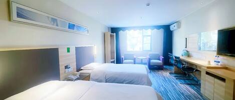 A hotel room with two beds, a desk, a chair, a TV, and a window.