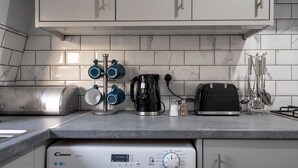 A kitchen with a built-in washing machine, a coffee maker, a toaster, and a kettle. - Modern Flat in Waterloo - Central London (London)