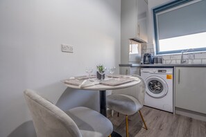 Cuina funcional amb rentadora, taula de dinar i caires, i finestra sobre l'evador.