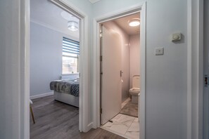 Un bany modern amb vàter, dutxa i finestra amb persianes.