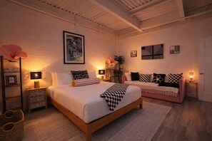 Une chambre à coucher avec un grand lit, un canapé, des tables de chevet avec des lampes et une œuvre d’art accrochée au mur.
