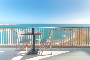 Ein Balkon mit Tisch und Stühlen mit Blick auf einen Strand.