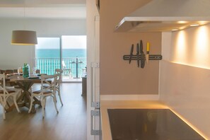 A dining area with a table and chairs, a view of the ocean, and a wall-mounted knife set. - Perfect seaside getaway: Cozy apartment with spectacular views in Sant Antoni de Calonge 🌅⚓ (Sant Antoni de Calonge)