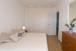A bedroom with a bed, bedside table, dresser, and a potted plant. - Perfect seaside getaway: Cozy apartment with spectacular views in Sant Antoni de Calonge 🌅⚓ (Sant Antoni de Calonge)