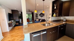 A modern kitchen with granite countertops, stainless steel appliances, and pendant lighting.