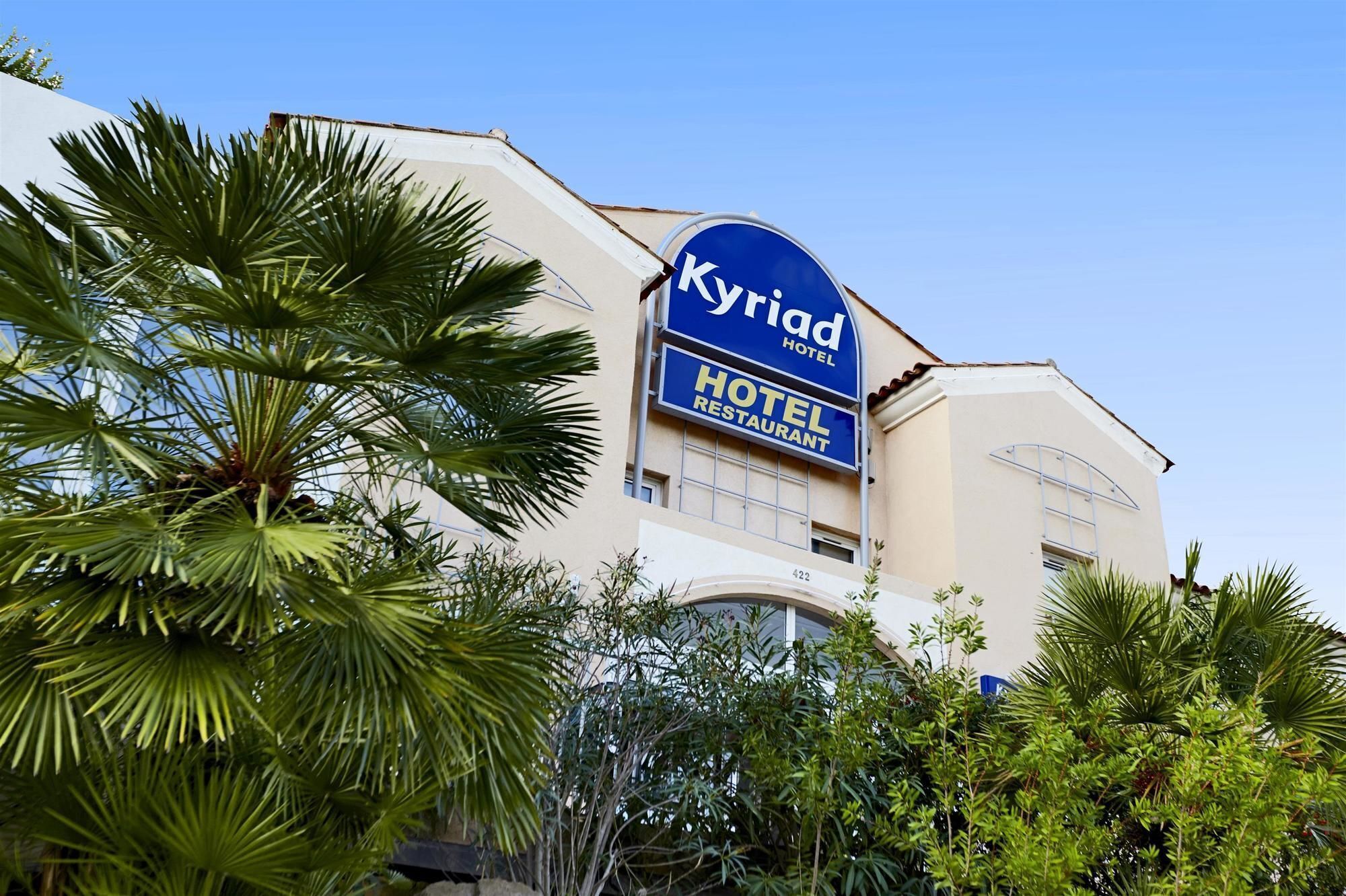 A hotel with a prominent sign reading 'Kyriad Hotel Restaurant' and the number '422' on the building.