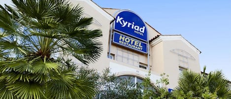 A hotel with a prominent sign reading 'Kyriad Hotel Restaurant' and the number '422' on the building.