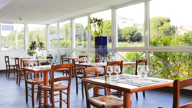 Een restaurant met grote ramen, houten tafels en stoelen.