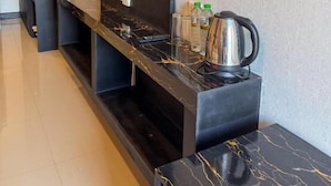 Ett modernt kök med en bänkskiva i marmor, en vattenkokare och en platt-TV som är monterad på väggen.