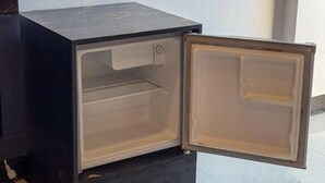 Ett litet kylskåp i mörk färg med en öppen dörr, vilket avslöjar dess tomma inre.