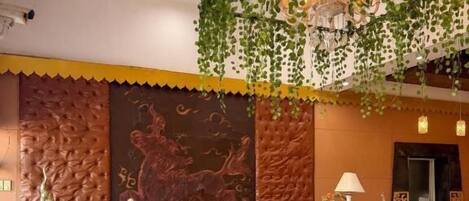 A reception area with a counter, chairs, a table with a floral tablecloth, and decorative wall panels.
