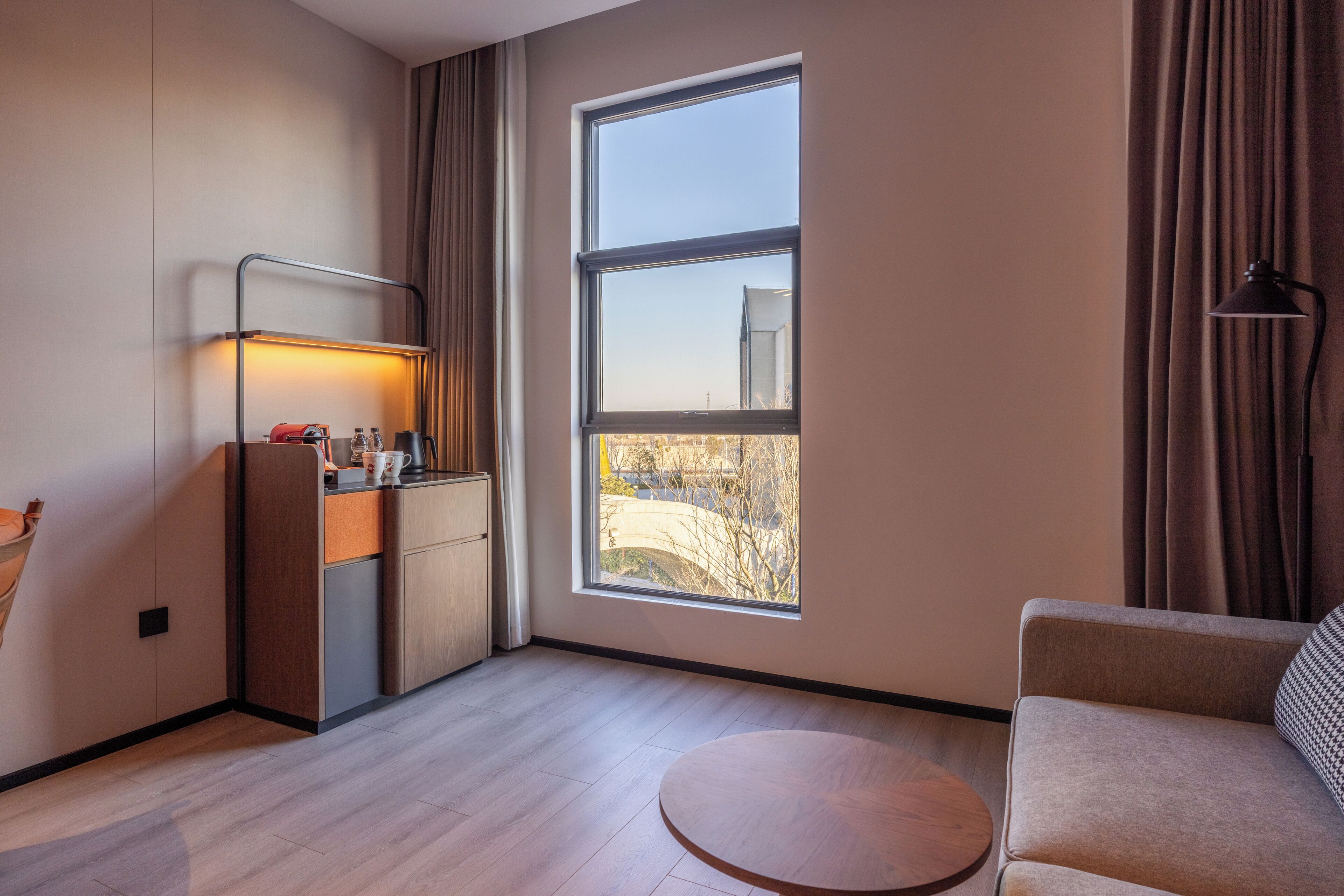 Habitación moderna con sofá, una mesa redonda, kitchenette y un amplio ventanal con vistas.