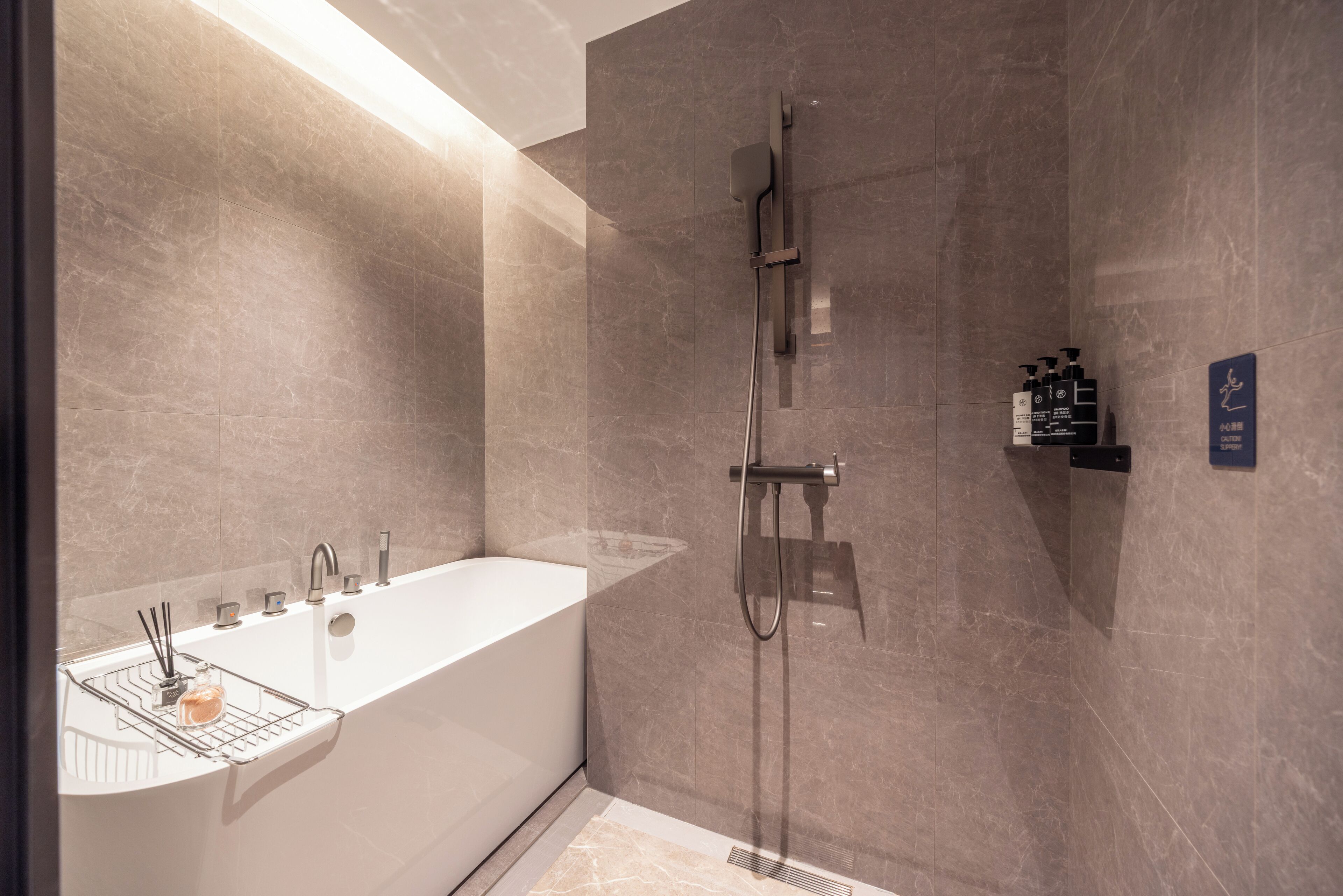 Un baño moderno con una bañera independiente, un cabezal de ducha y un estante en la pared con artículos de aseo.