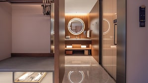 A modern bathroom with a round mirror, wooden vanity, and a towel rack. - UrCove by Hyatt Taicang South Railway (Suzhou)