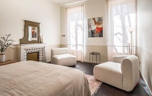 A hotel room with a bed, two armchairs, a fireplace, and artwork on the walls. - Maison piscine proche Alpilles (Alleins)