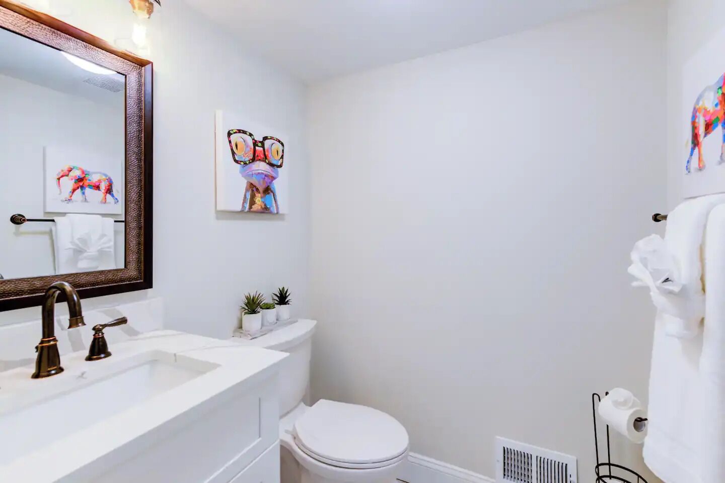 Une salle de bain avec un lavabo blanc, des toilettes, un miroir et un porte-serviettes.