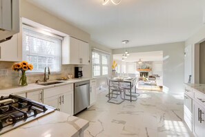 A modern kitchen with white cabinets, a stainless steel dishwasher, and a marble countertop. - Sunset Point 4 Bedroom Home by D&R canal (Princeton)