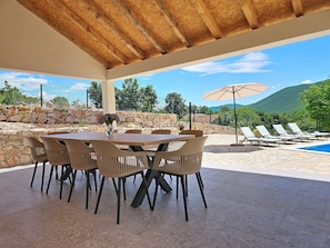 An outdoor patio with a table and chairs, a pool, and a view of mountains. - Vacation home Dripić by Interhome (Imotski)