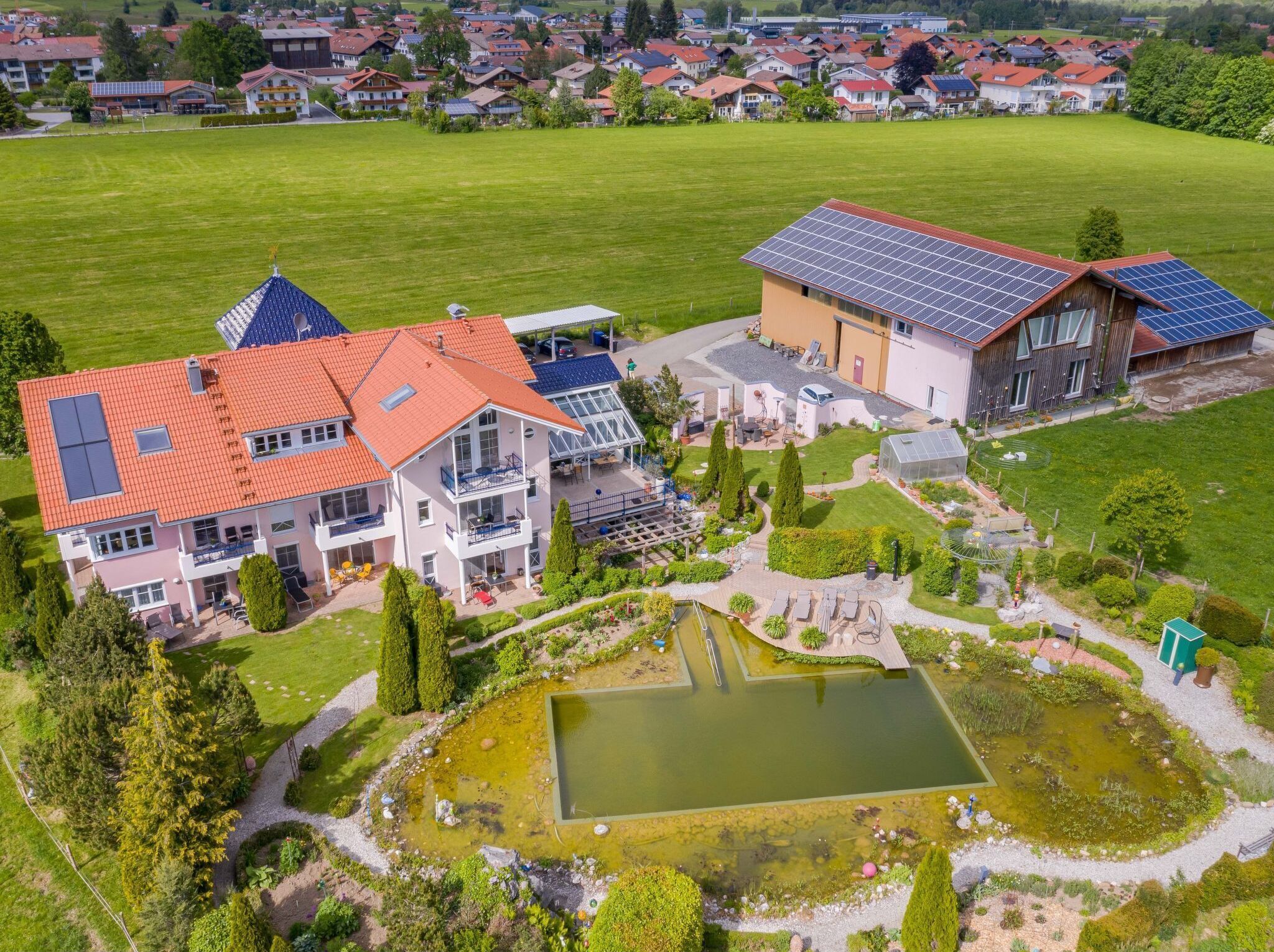 A large house with multiple balconies, a swimming pool, and solar panels.