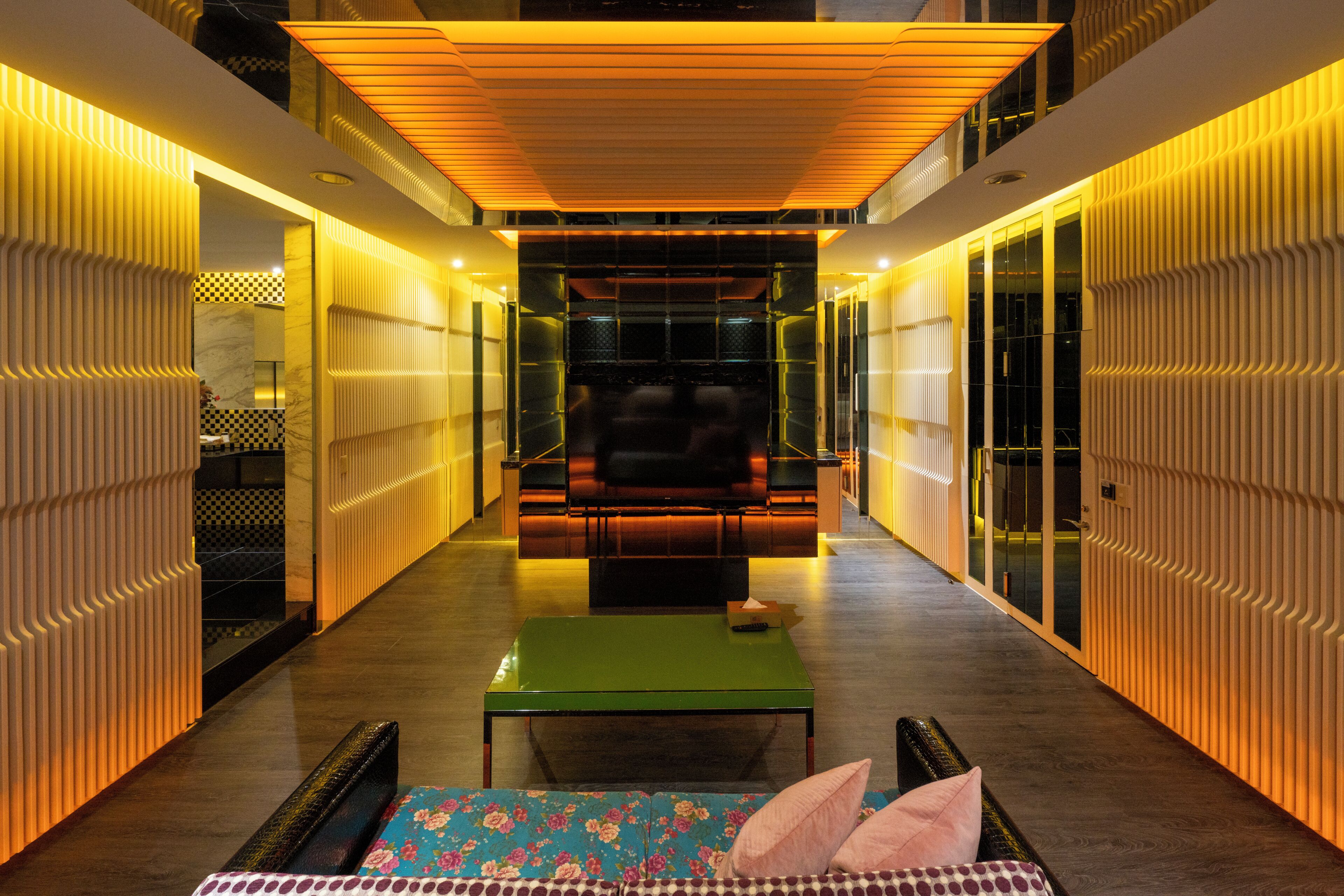 Un interior moderno con una zona de estar central, una mesa verde y un sofá estampado.