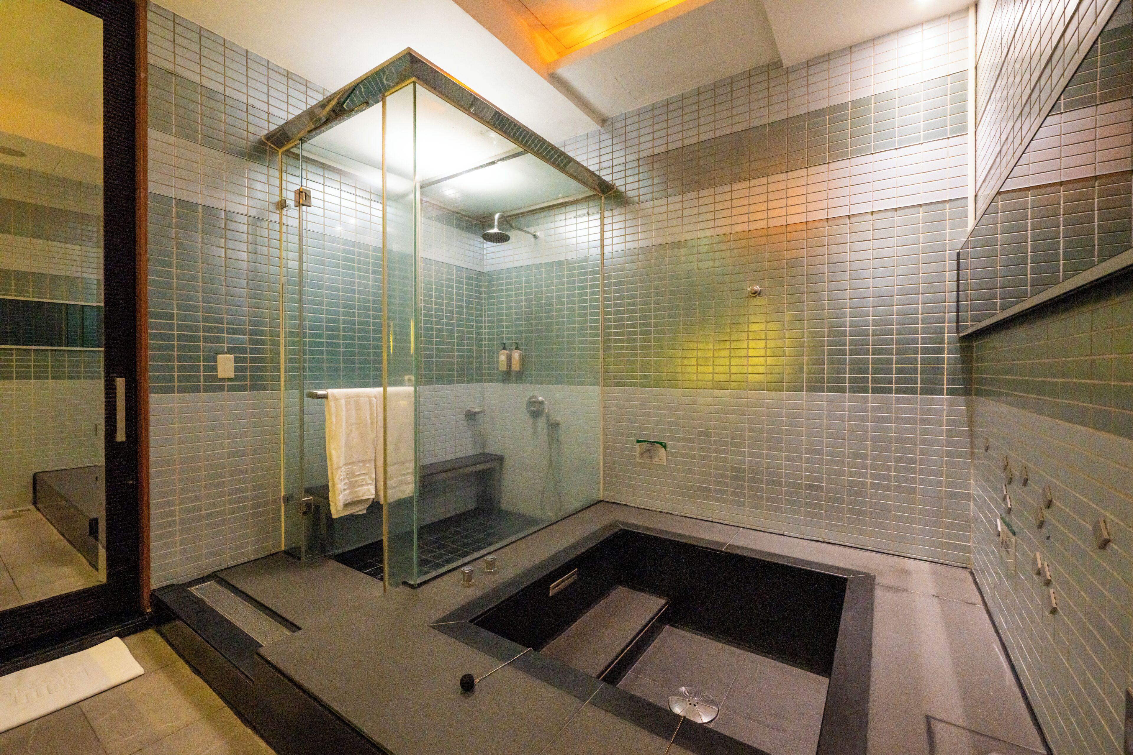 Un baño moderno con ducha acristalada, bañera independiente y suelo de baldosas.