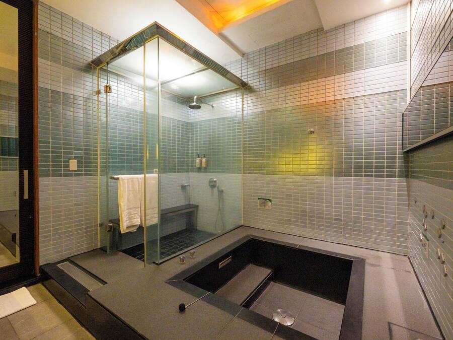 Un baño moderno con ducha acristalada, bañera independiente y suelo de baldosas.