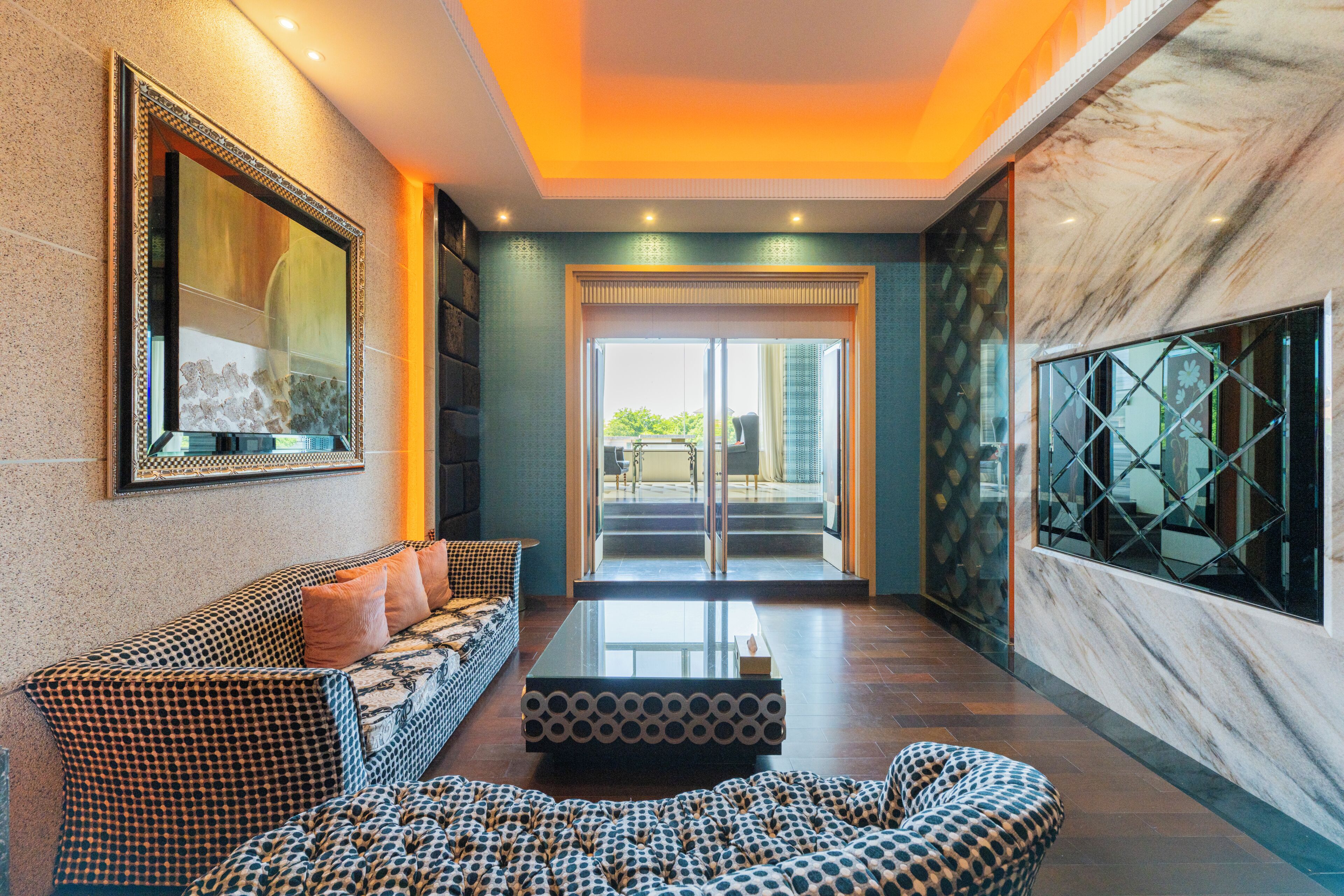 A modern lobby with a patterned sofa, a coffee table, and a large mirror.