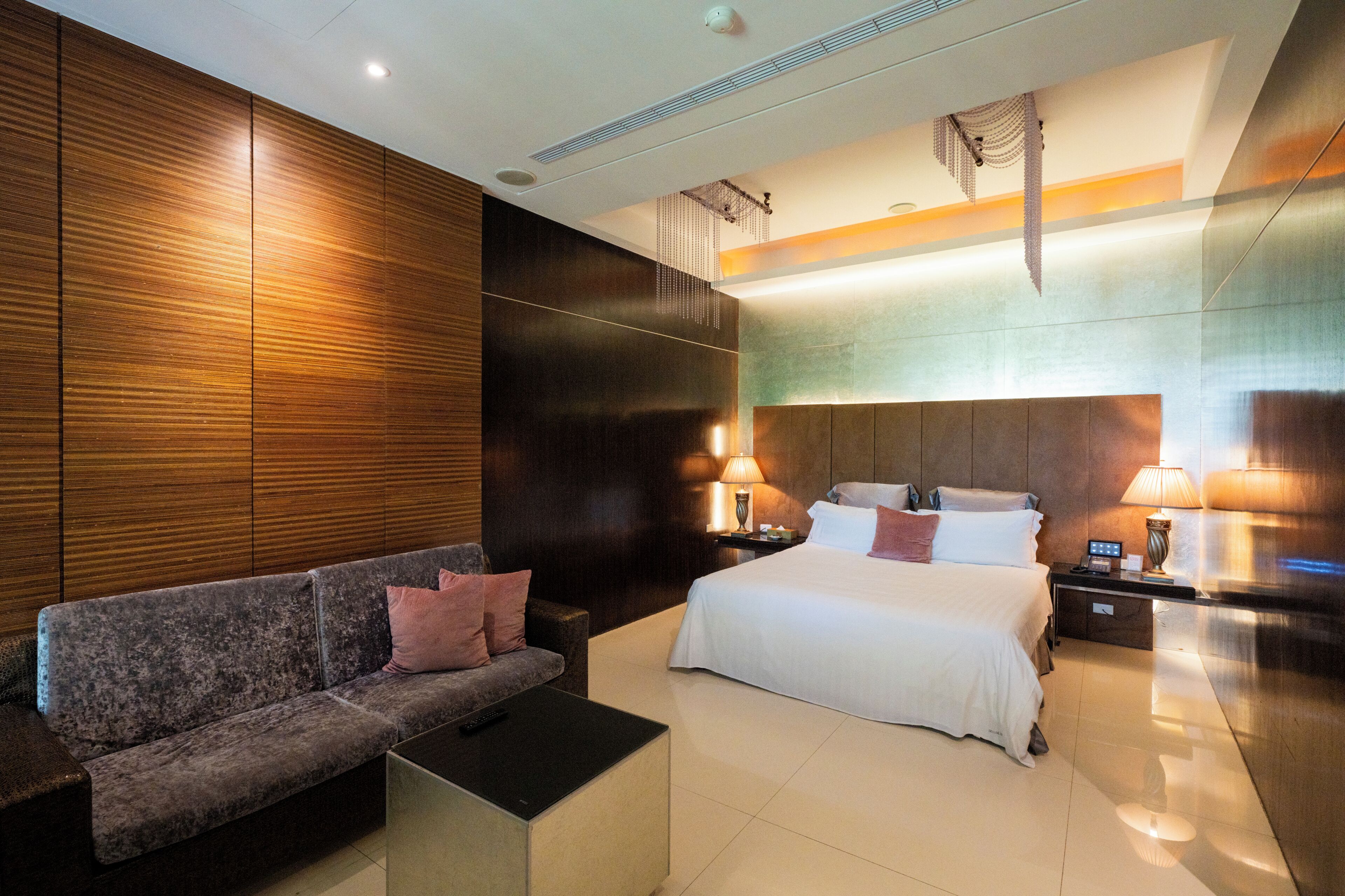 Une chambre d’hôtel moderne avec un lit, un canapé et des tables de chevet.