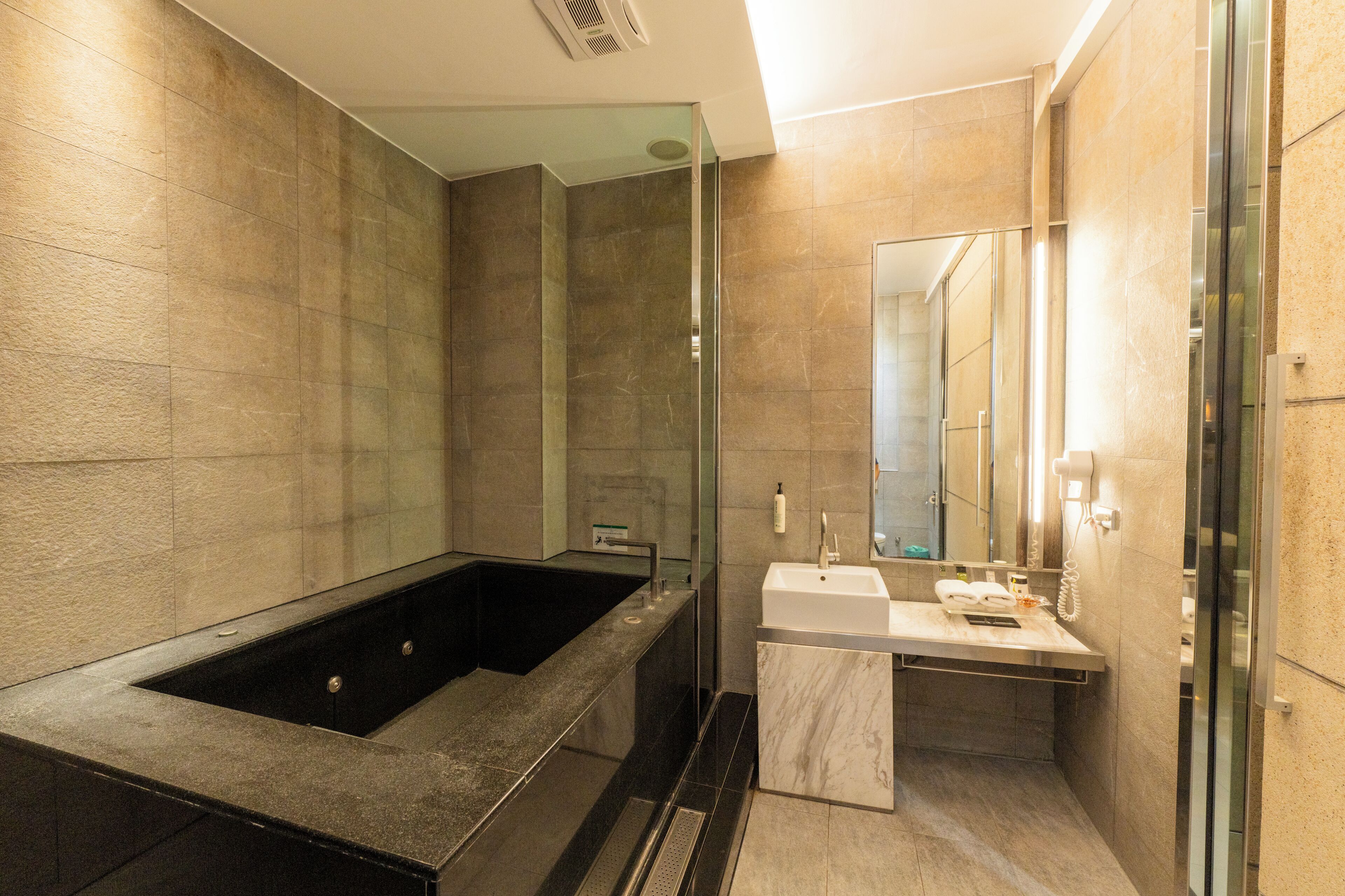 A modern bathroom with a large bathtub, a sink, and a mirror.