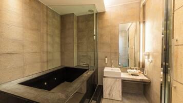 A modern bathroom with a large bathtub, a sink, and a mirror.