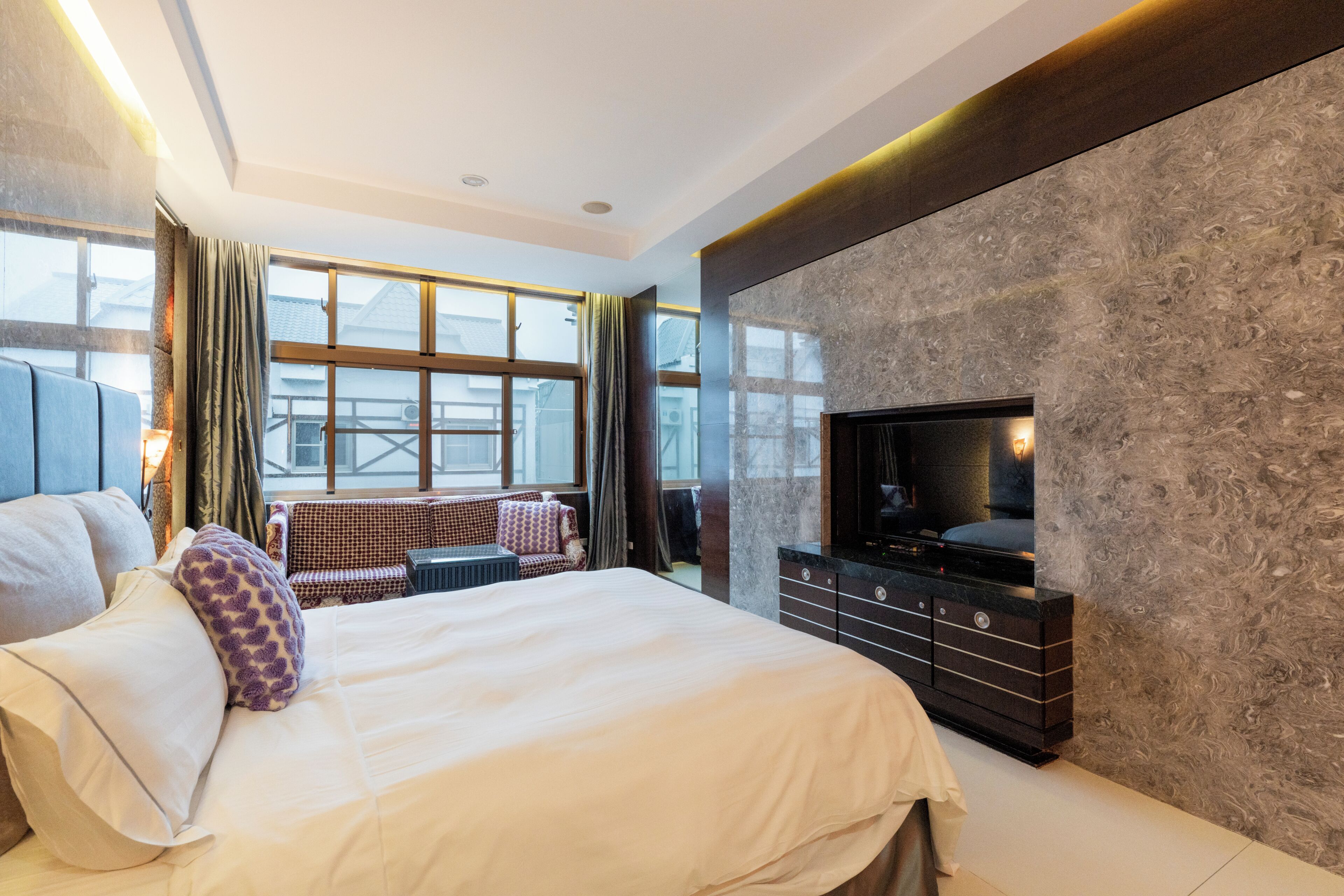 Une chambre d’hôtel moderne dotée d’un grand lit, d’une télévision, d’un coin salon avec vue et d’une cheminée.