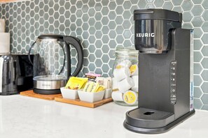 Eine Keurig-Kaffeemaschine auf einer Küchenarbeitsplatte mit einer Rückwand aus sechseckigen Fliesen.