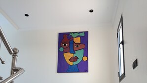 Un pasillo con una escalera, una obra de arte en la pared y una ventana.