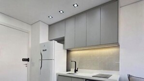 Een moderne keuken met een ingebouwde magnetron, een koelkast en een aanrecht.