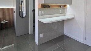 Een moderne keuken met een inbouw eiland, grijze kastjes en een spiegel boven het aanrecht.
