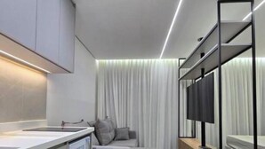 Een moderne keuken met een ingebouwde oven, een grijze bank, een houten bijzettafeltje en een grote spiegel.