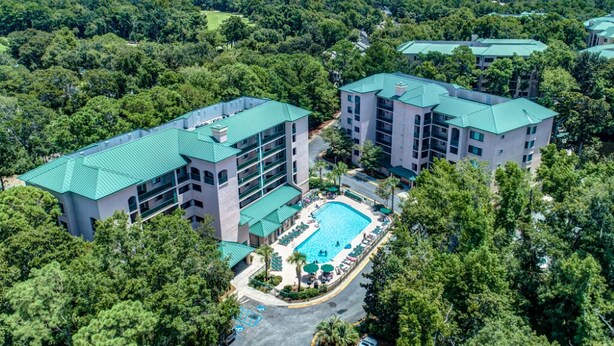 Um resort com vários edifícios, piscina e vegetação exuberante ao redor da propriedade.