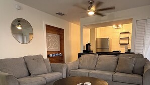 Ein Wohnzimmer mit einem Ecksofa, einem runden Couchtisch und einem Deckenventilator.